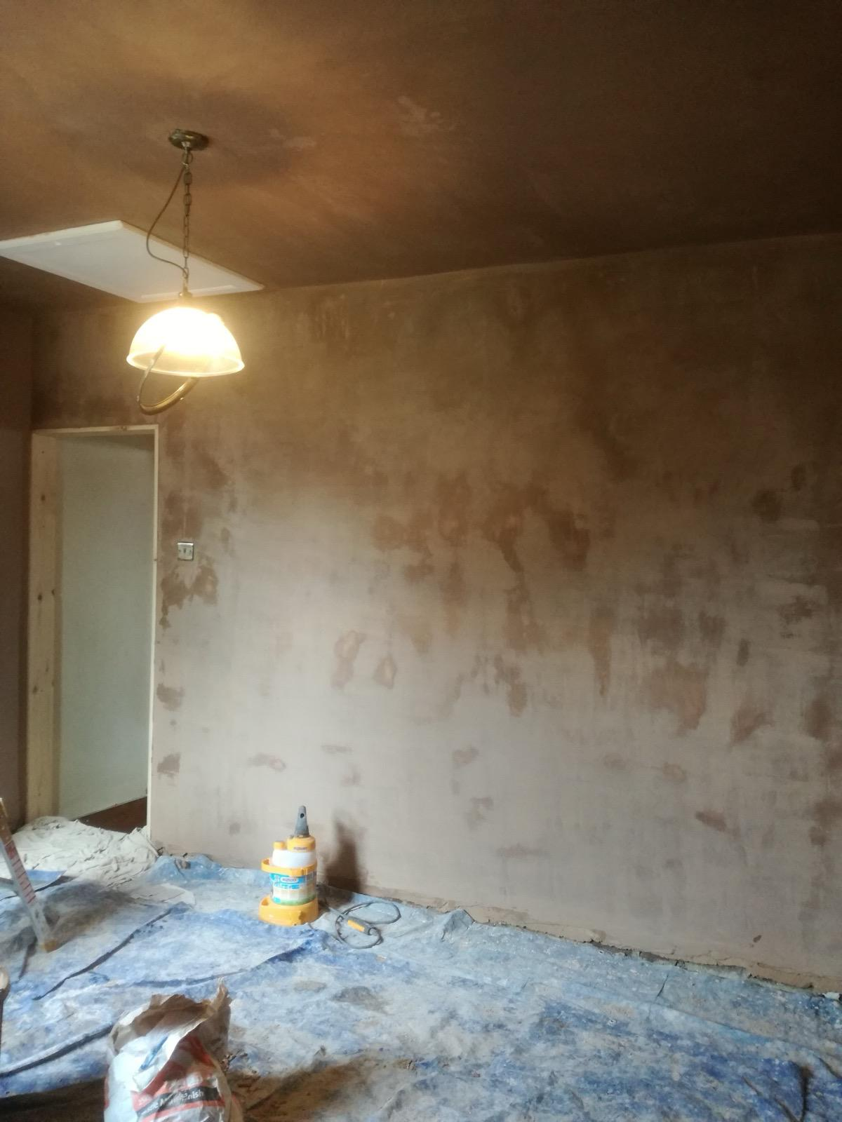 Fresh plaster drying on an interior wall and ceiling, with the floor covered for work