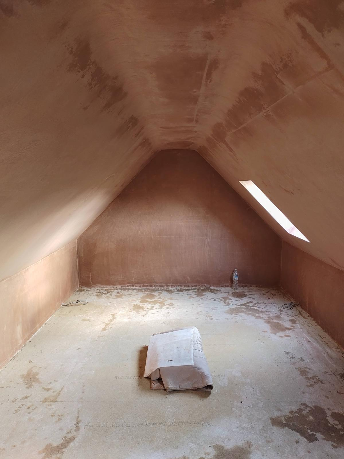 Newly plastered loft walls and sloping ceiling drying with roof window