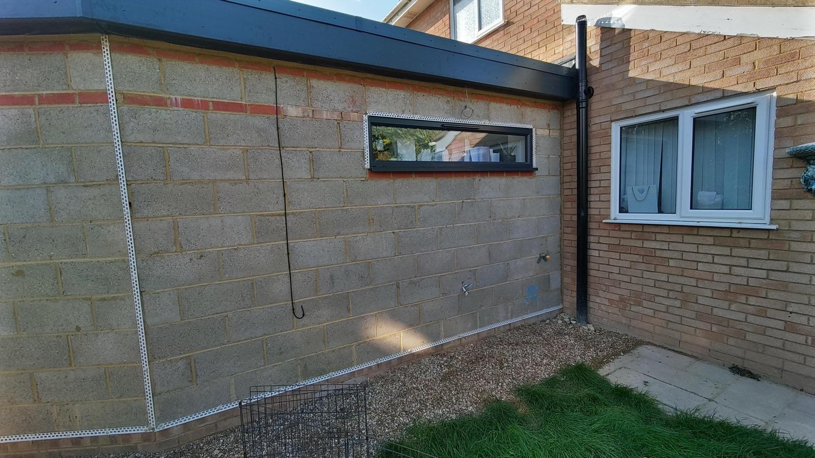 Blockwork extension wall with render beads around a slim window