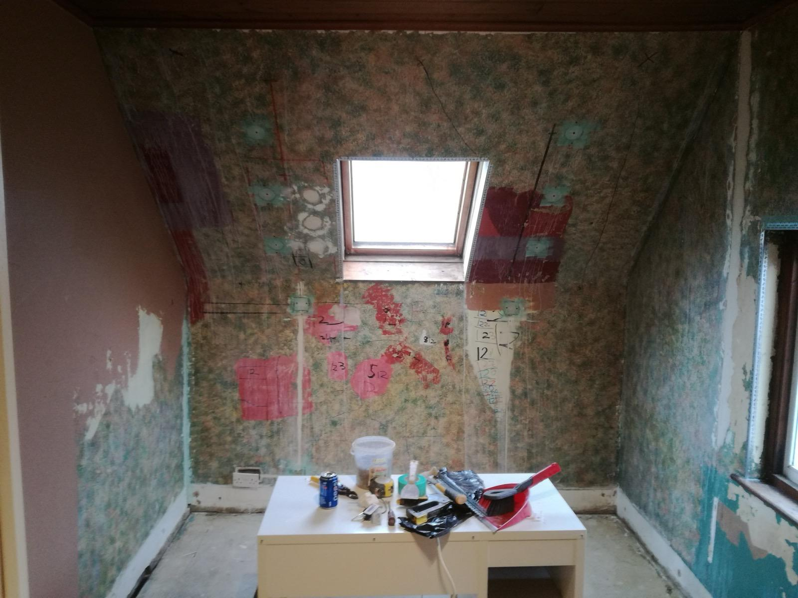 Room with stripped walls and a roof window before plastering