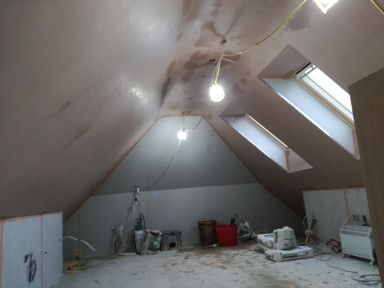 Fresh plaster on a sloping loft ceiling around two roof windows