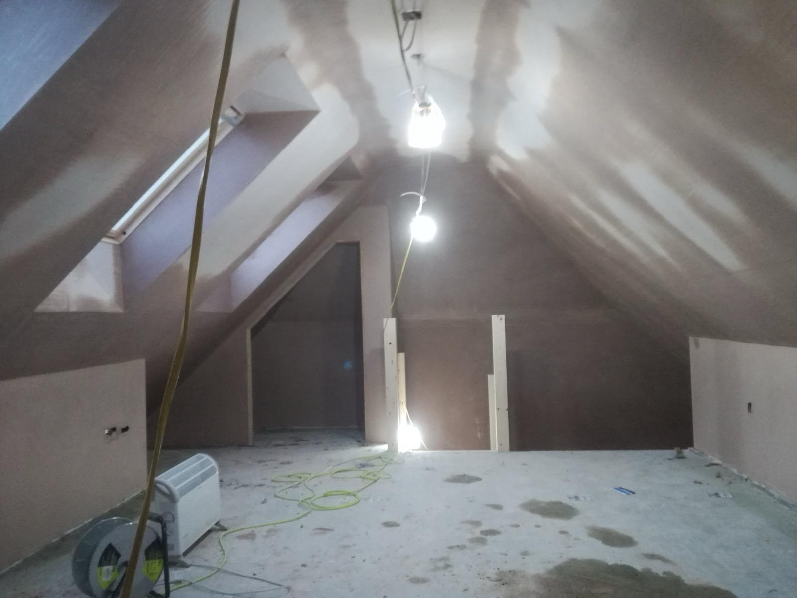 Pitched loft ceiling and walls with fresh plaster and visible drying marks
