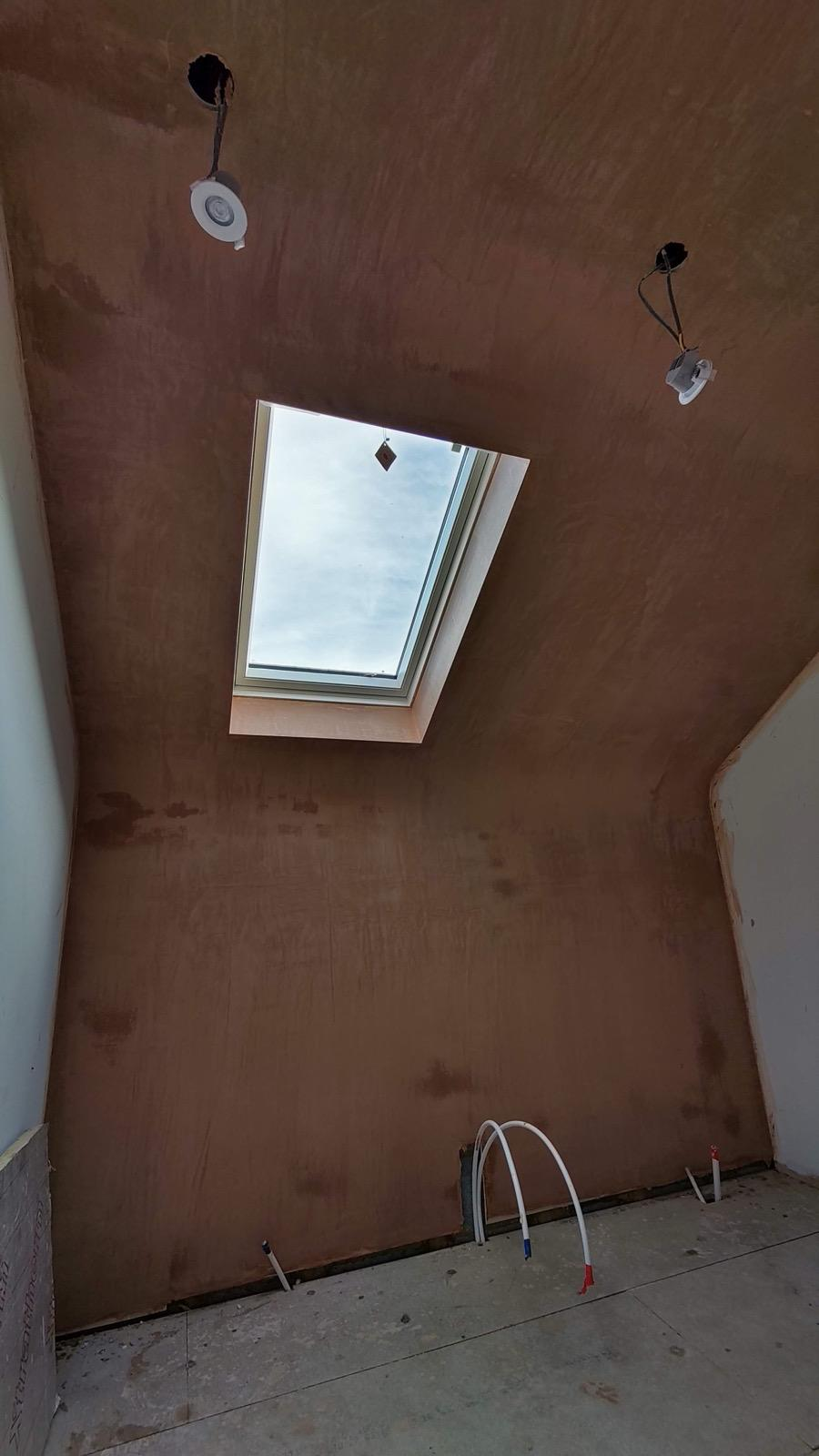Freshly plastered sloped ceiling and wall around a roof window