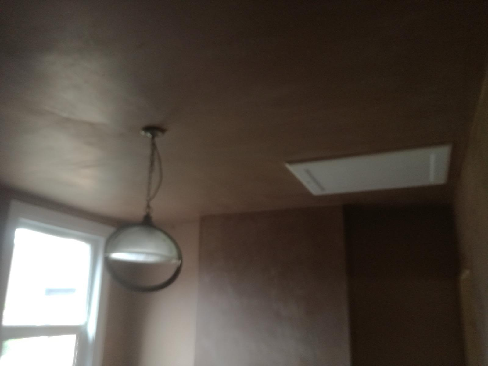 Newly plastered ceiling and walls near a window and hanging light