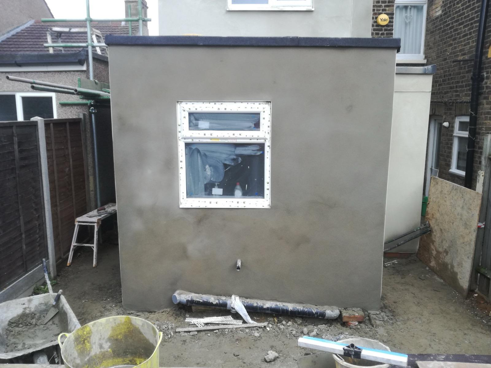 Fresh dark render on an exterior wall surrounding a white-framed window
