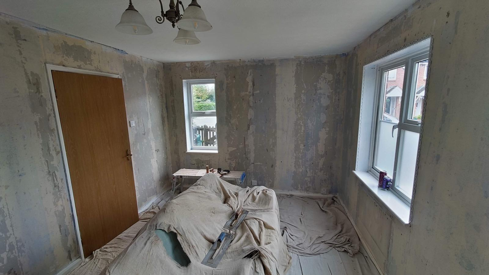 Bedroom walls stripped and prepared, with floor protected by dust sheets