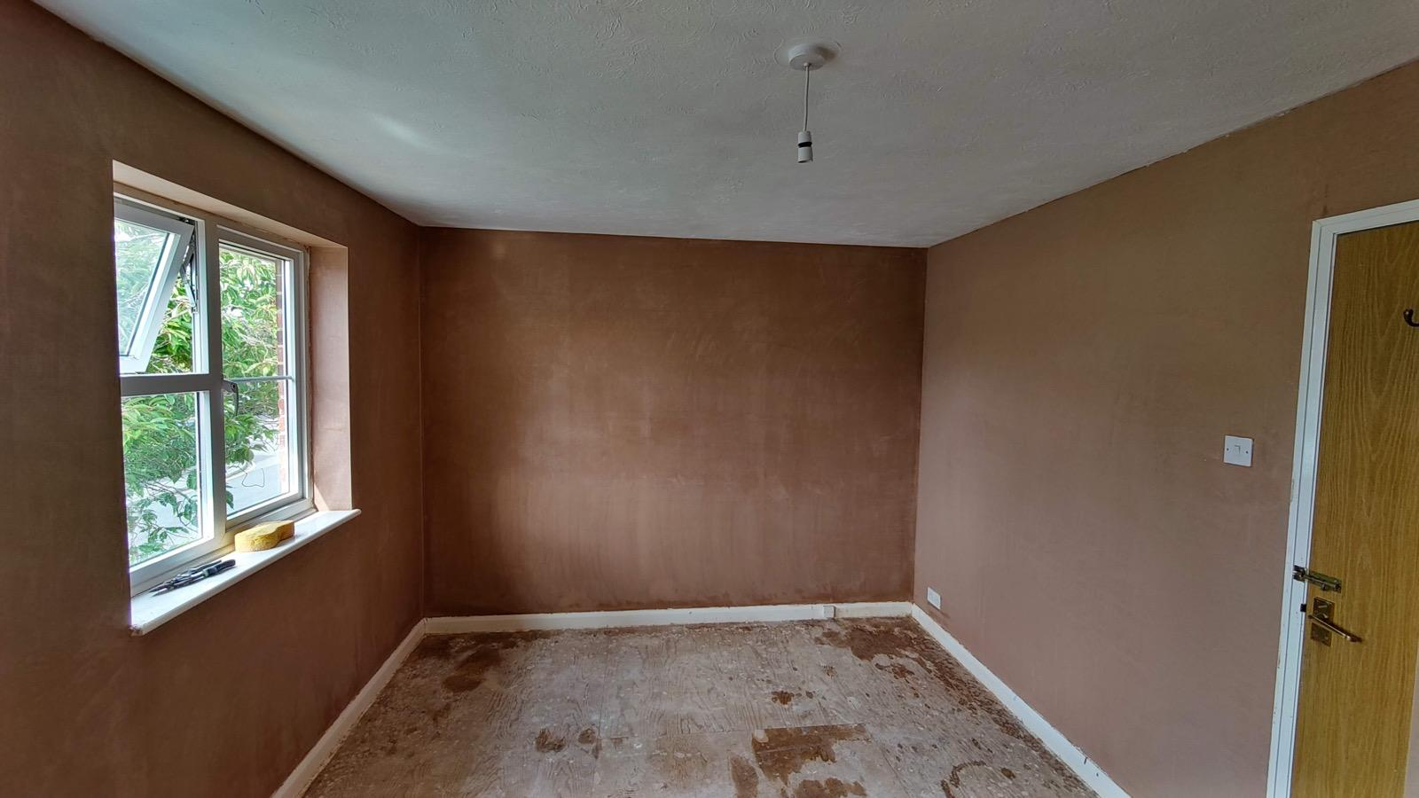 Freshly plastered room walls with a window and doorway