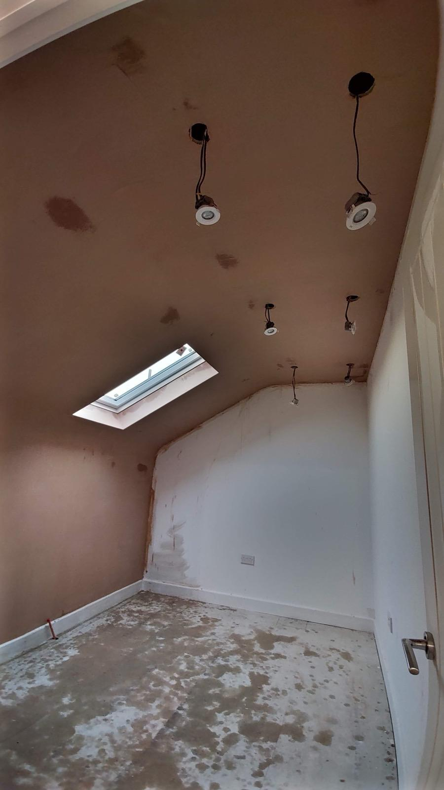 Fresh plaster on a sloped ceiling with recessed spotlight fittings