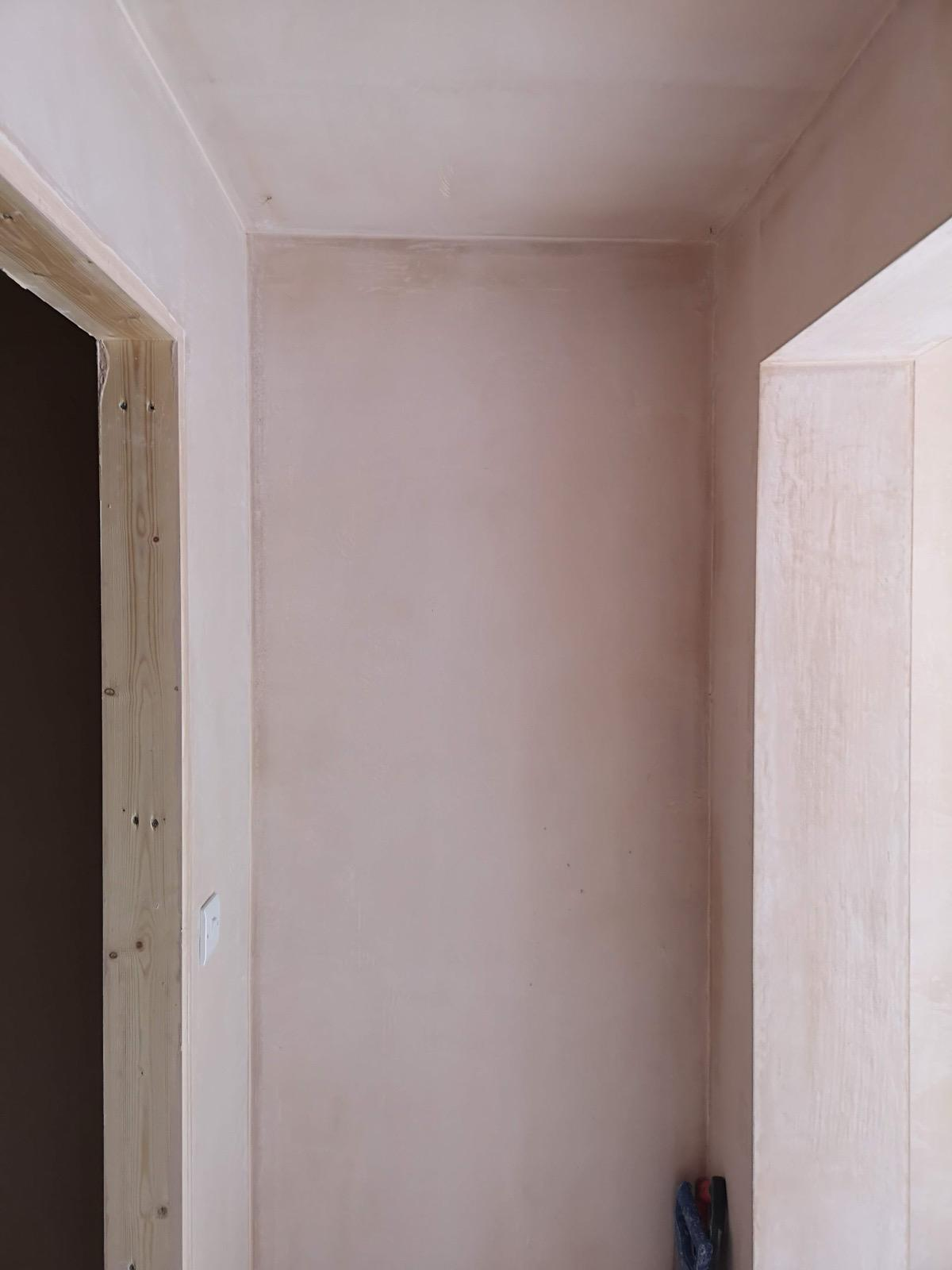 Newly plastered walls and ceiling of a narrow interior passage between two openings