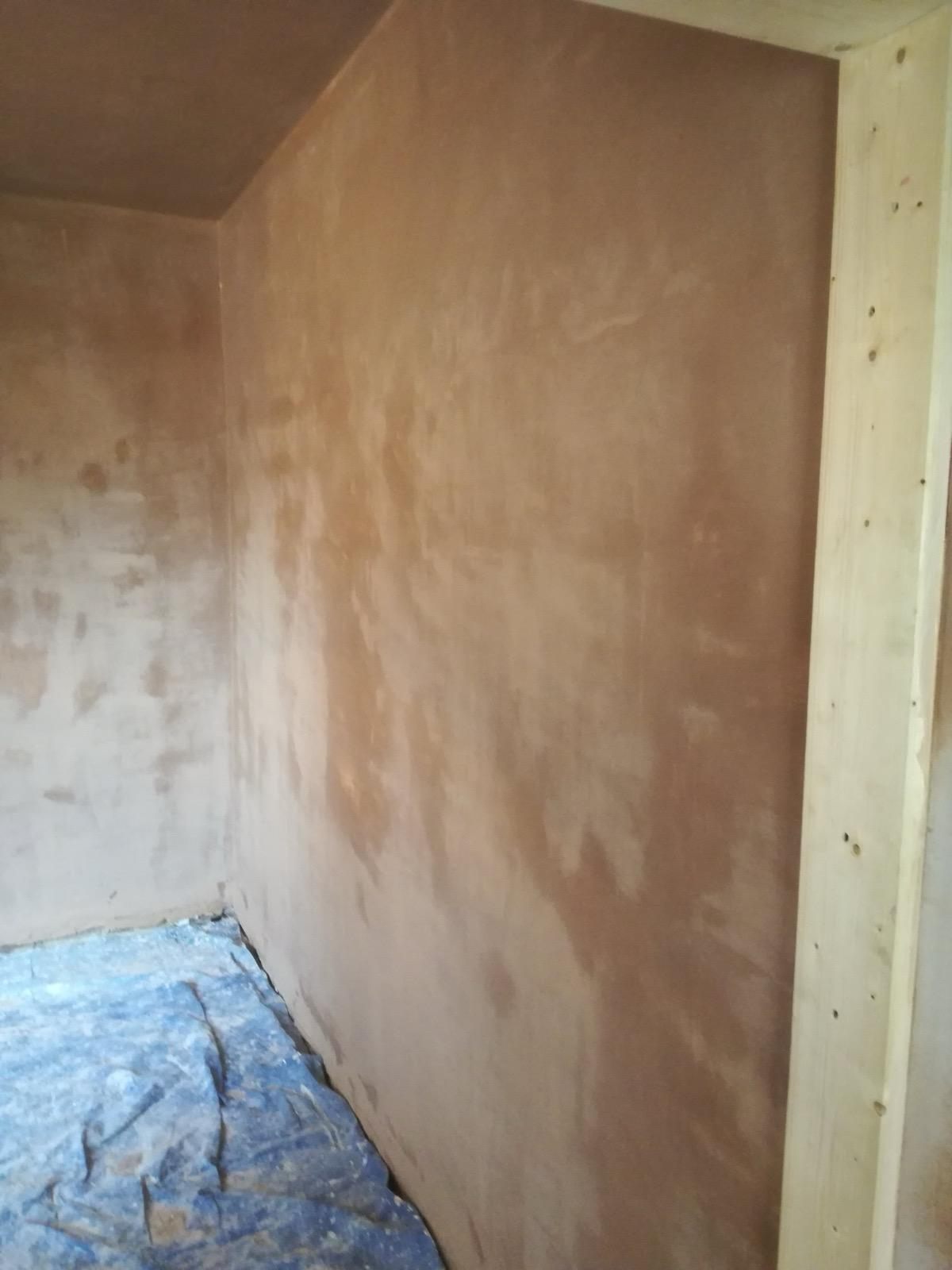 Fresh plaster on two adjoining walls, with a protective sheet covering the floor