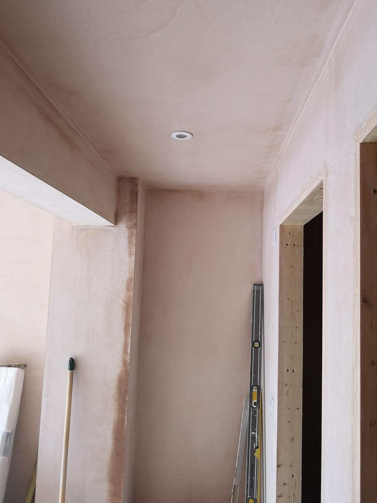 Fresh plaster on a hallway ceiling and walls, with timber door frames still exposed