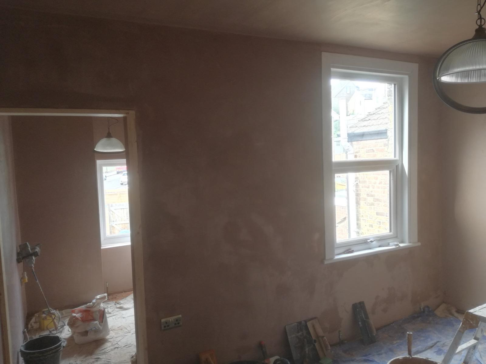 Freshly plastered interior walls around two white-framed windows