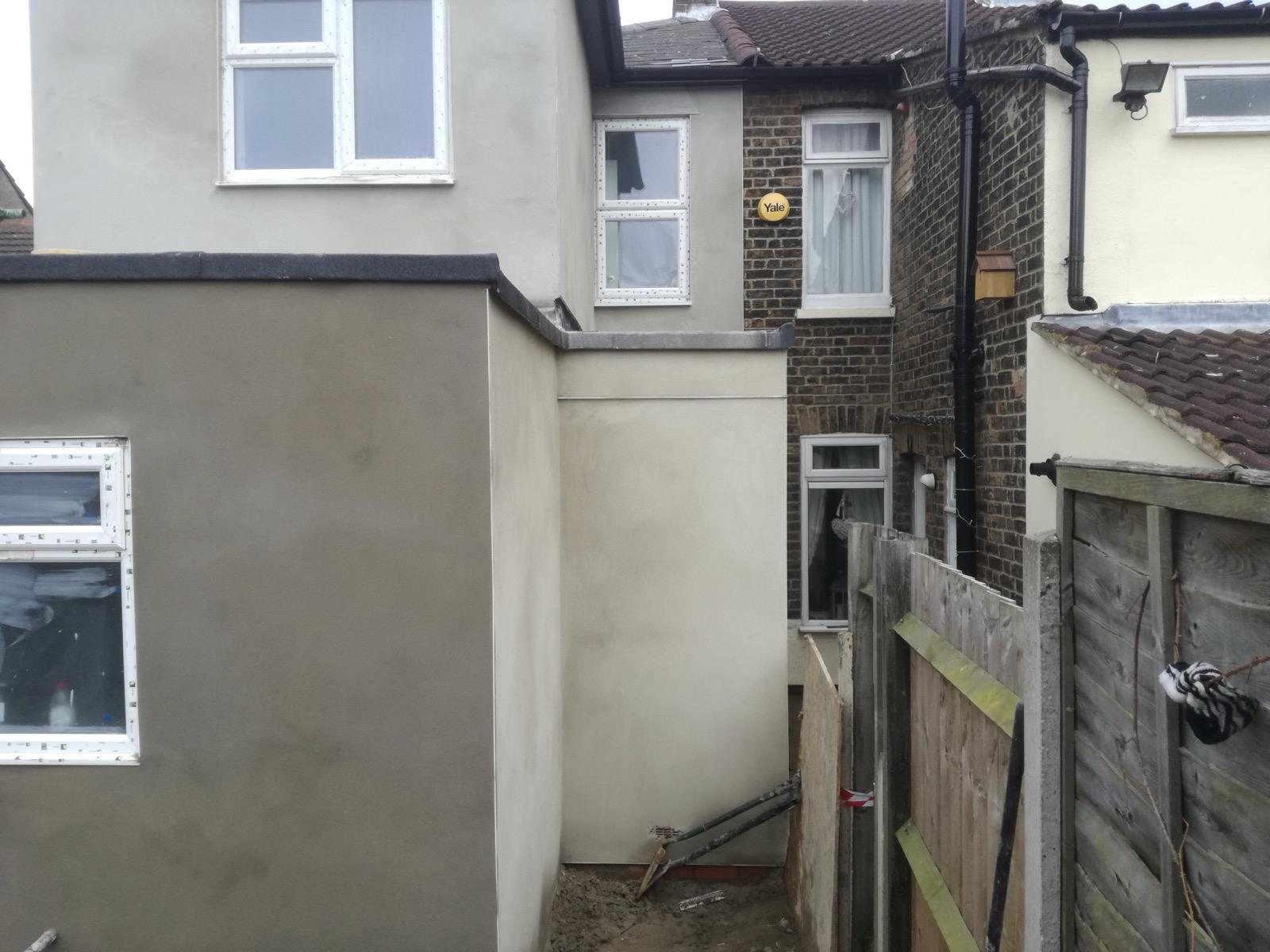 Side view of a rendered rear extension and adjacent rendered wall