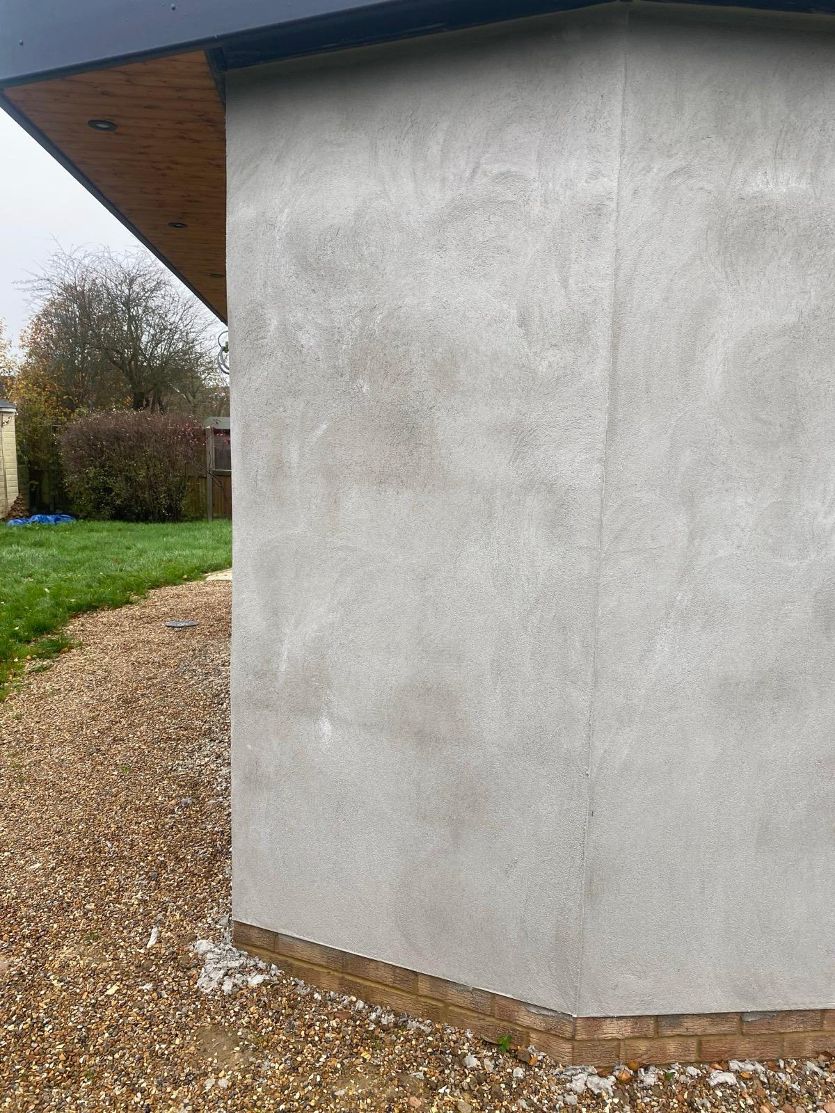 Grey render base coat applied around an exterior extension corner