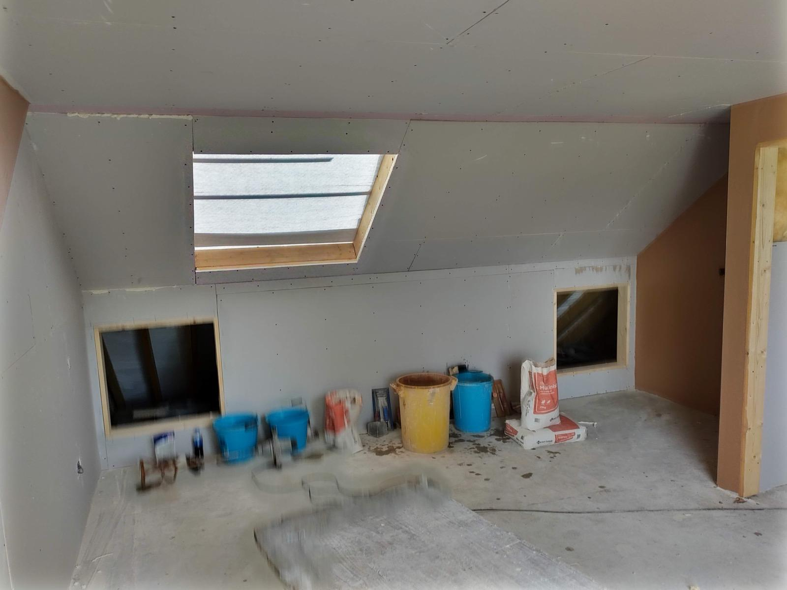 Boarded loft room with roof window and access hatches, before plastering