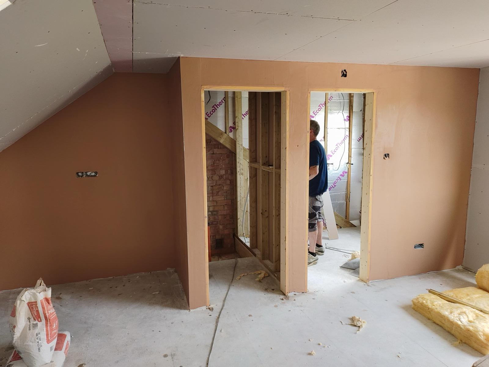 Fresh plaster on loft partition walls around two timber-framed doorways