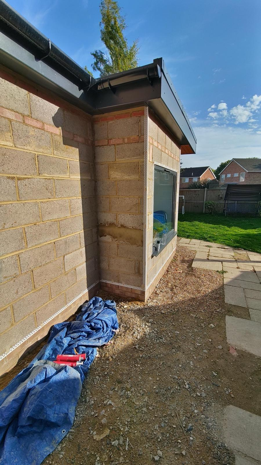 Blockwork extension corner fitted with render beads beside a window