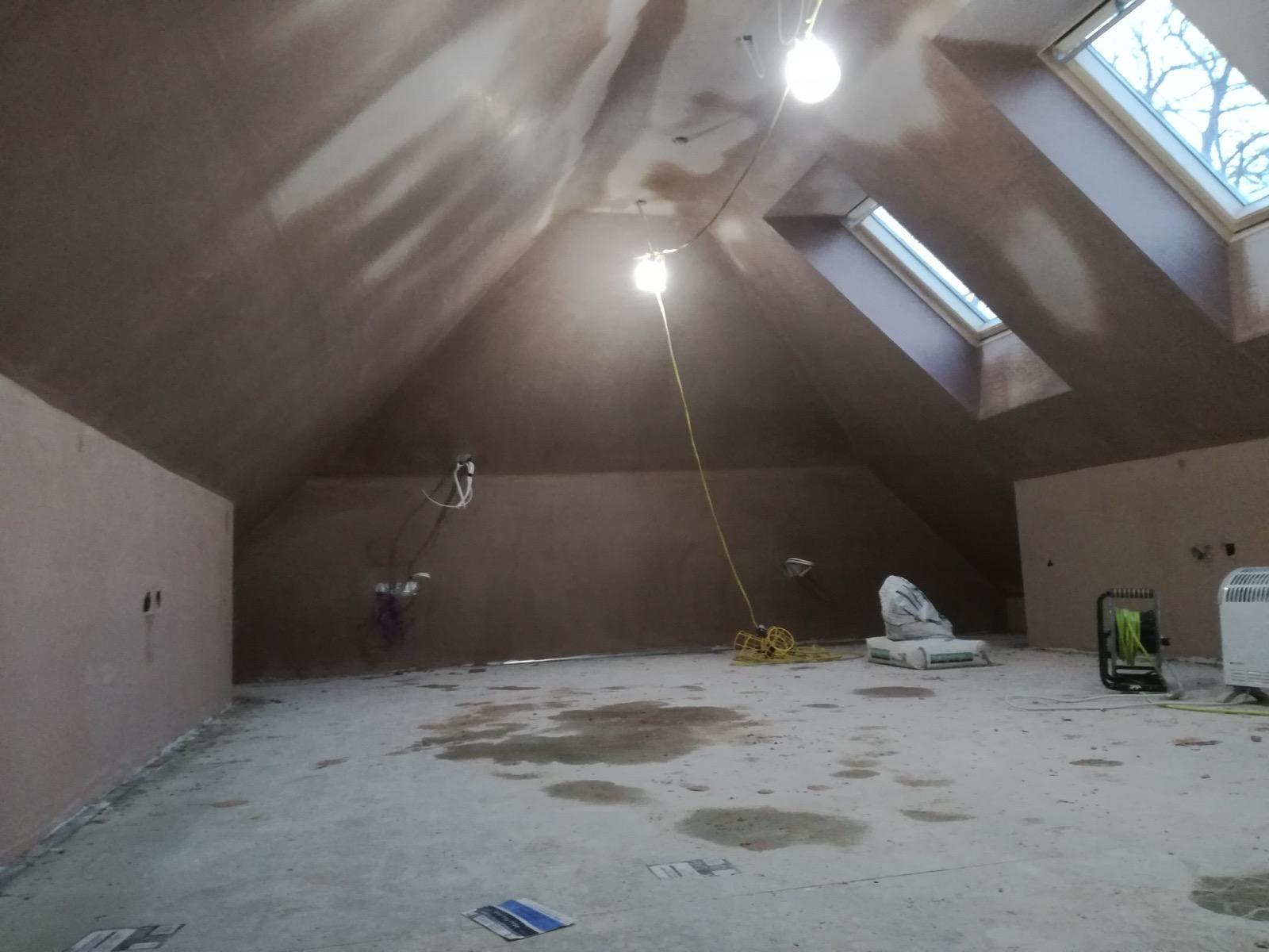 Wide view of a loft room with newly plastered walls and pitched ceiling