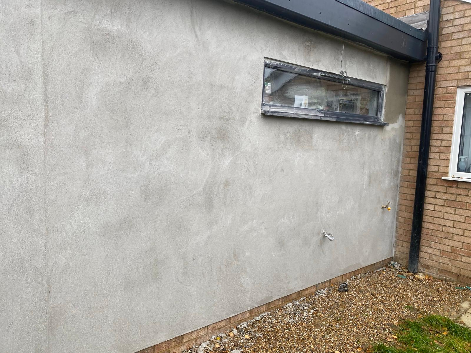 Grey rendered extension wall surrounding a slim horizontal window