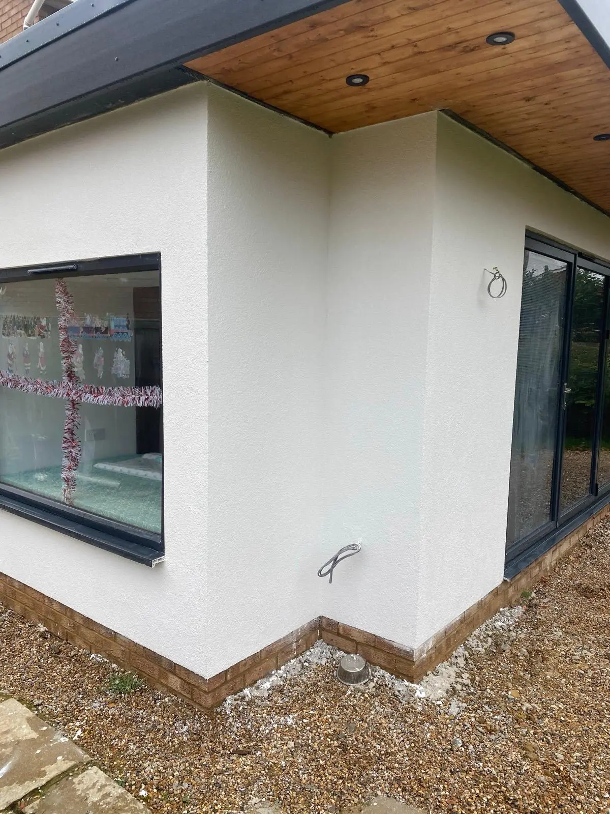 Finished rendered corner between a large window and glazed doors
