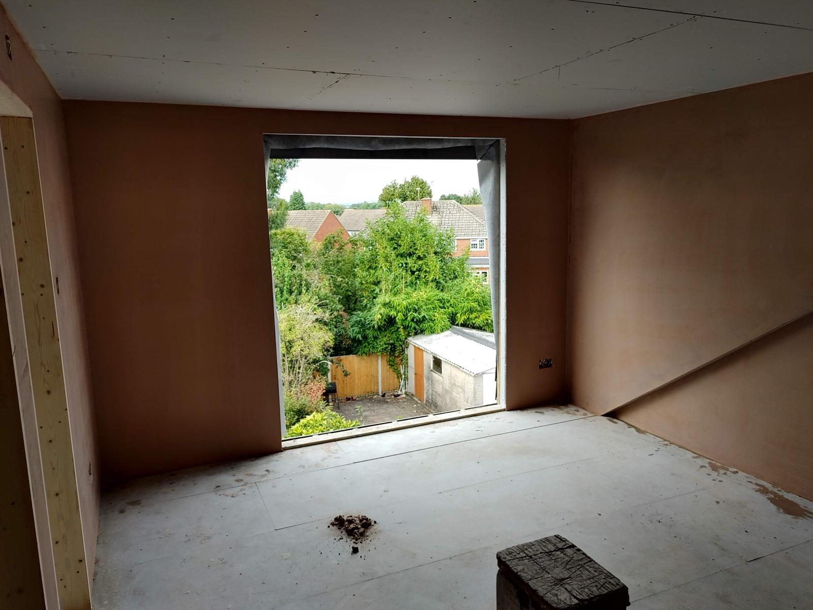 Freshly plastered walls in a dormer room with a large window opening